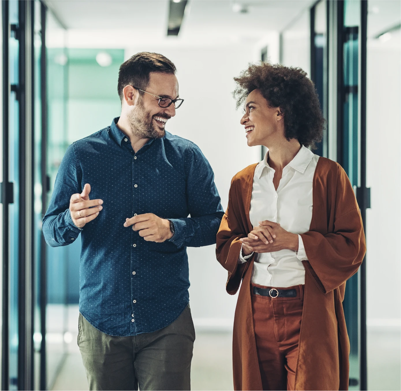 professional man and woman walking through office hallway and smiling