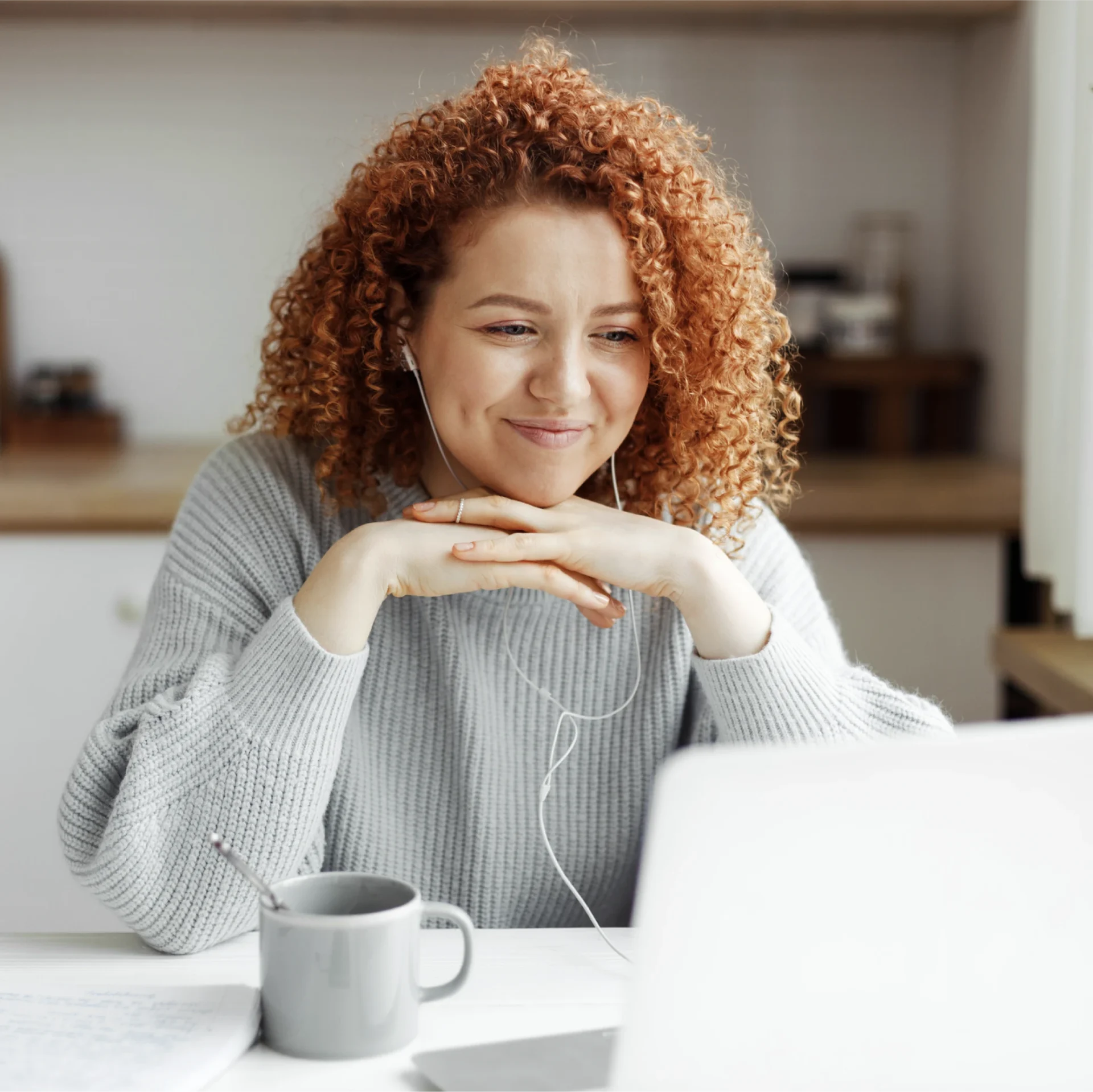 woman sitting at her laptop, drinking coffee and smiling